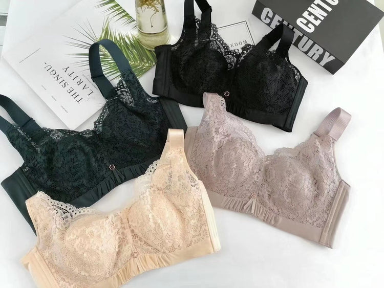 A variety of bras in beige, black, and other neutral tones, laid out neatly on a surface. The bras feature lace detailing and supportive wide straps.
