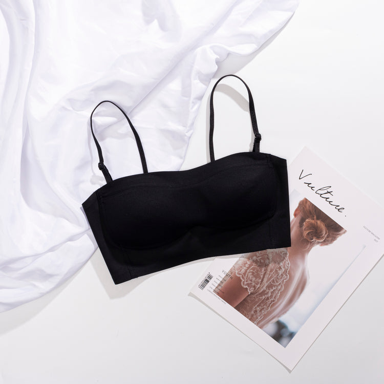 Front view of a black strapless bra displayed on a flat surface, with removable straps beside it.