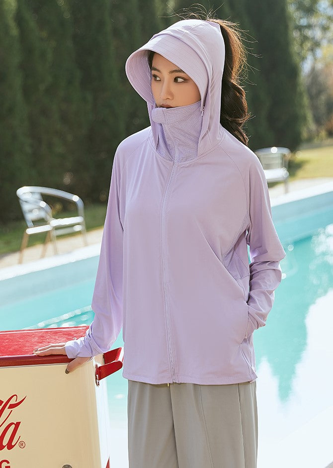 Woman standing by a pool, wearing a purple sun-protection jacket with a hood and face mask